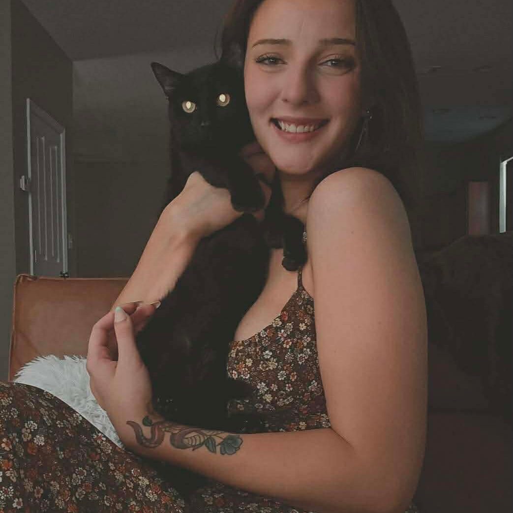 Woman smiling while holding a black cat.
