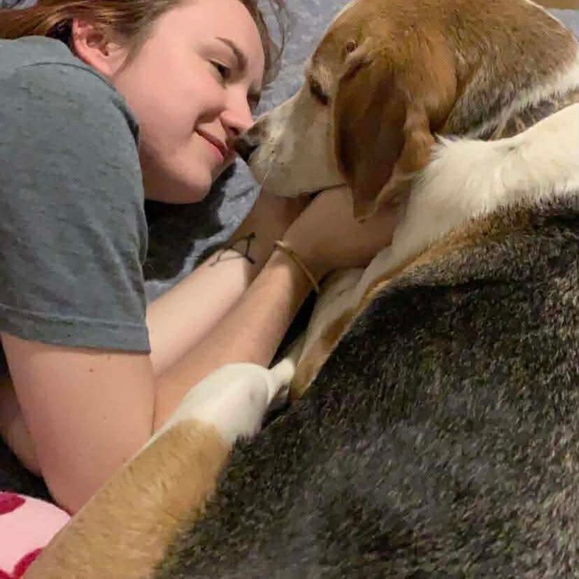 Woman and dog snuggling on bed.
