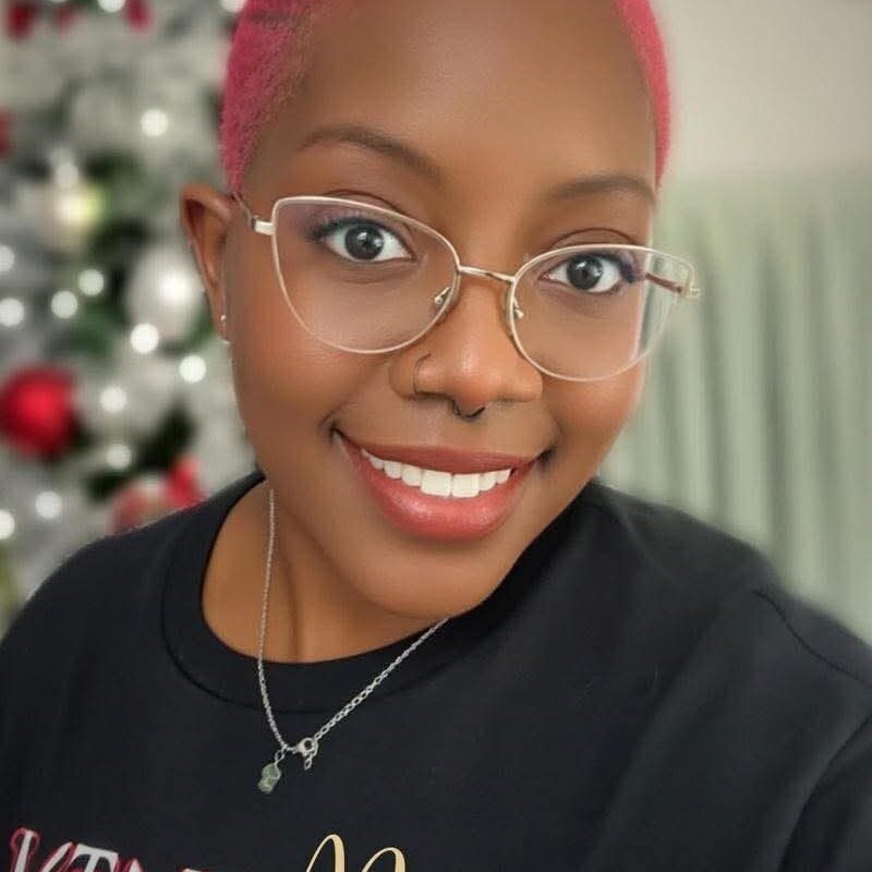 Smiling person with glasses, Christmas tree background.
