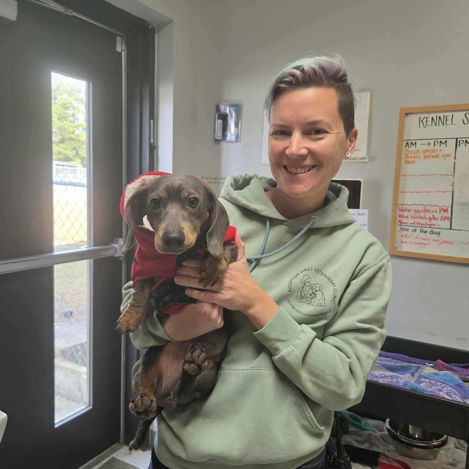 Person smiling and holding a small dog.