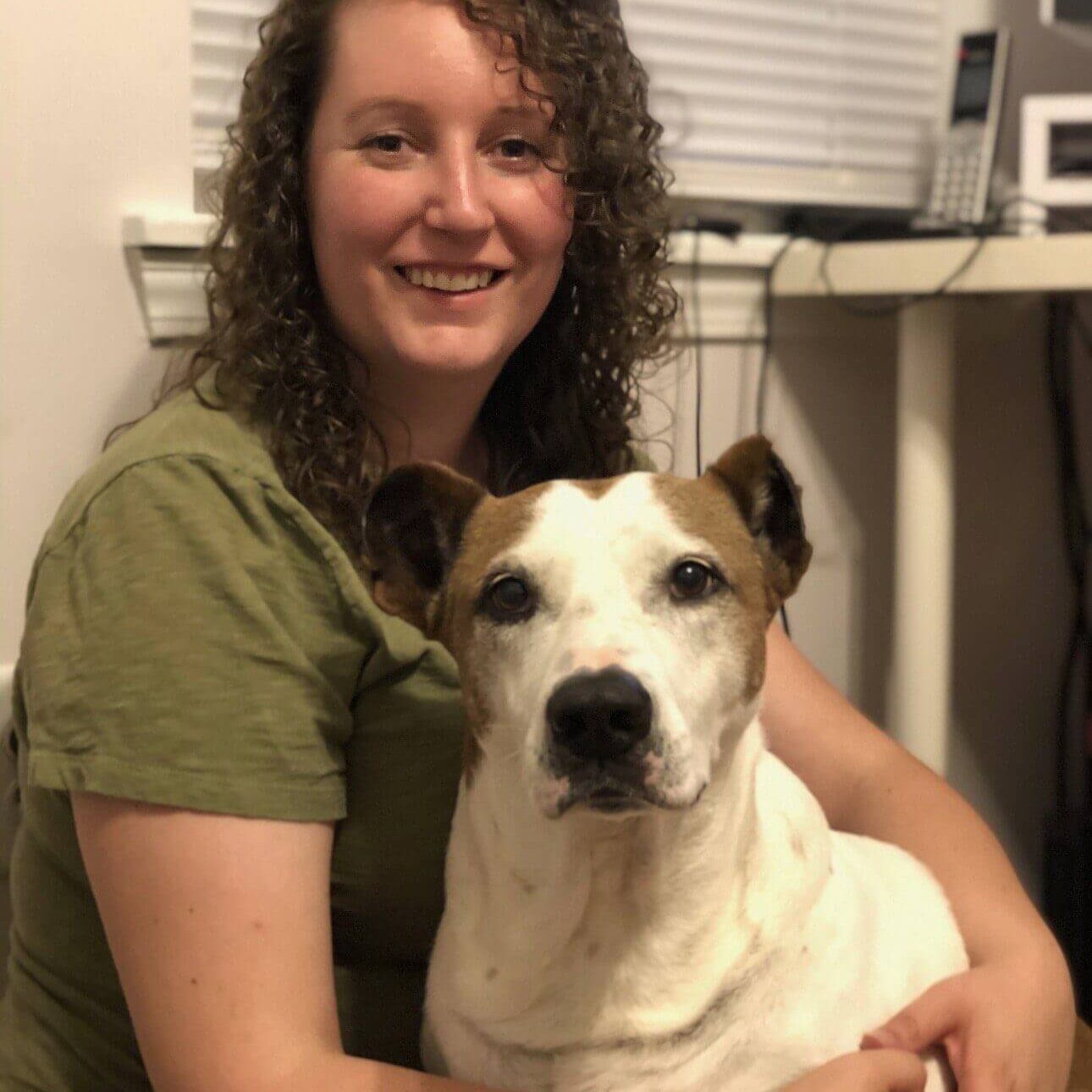 Woman hugging a white and brown dog.