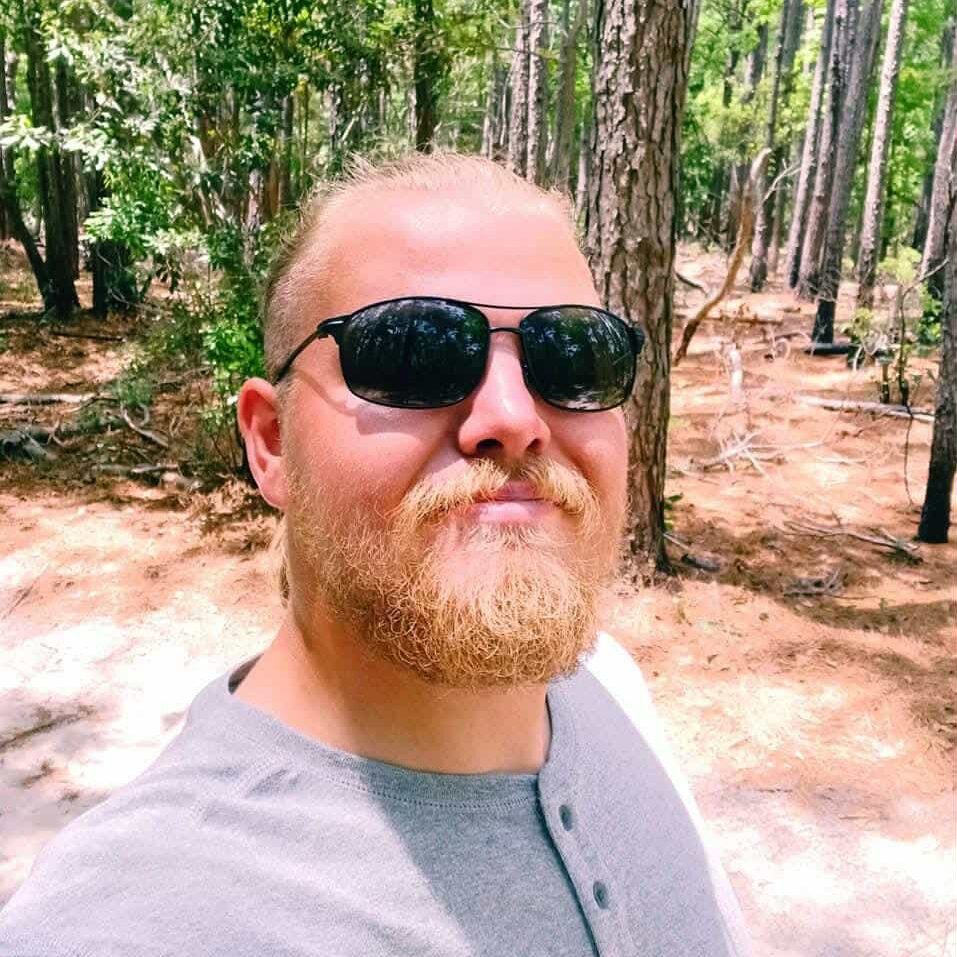 Man wearing sunglasses in a forest.